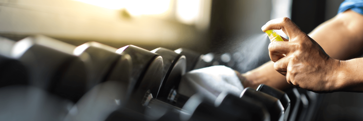 Man disinfecting free weights in a gym