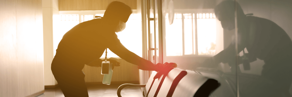 Man spraying and wiping chair in an office waiting area during sunset