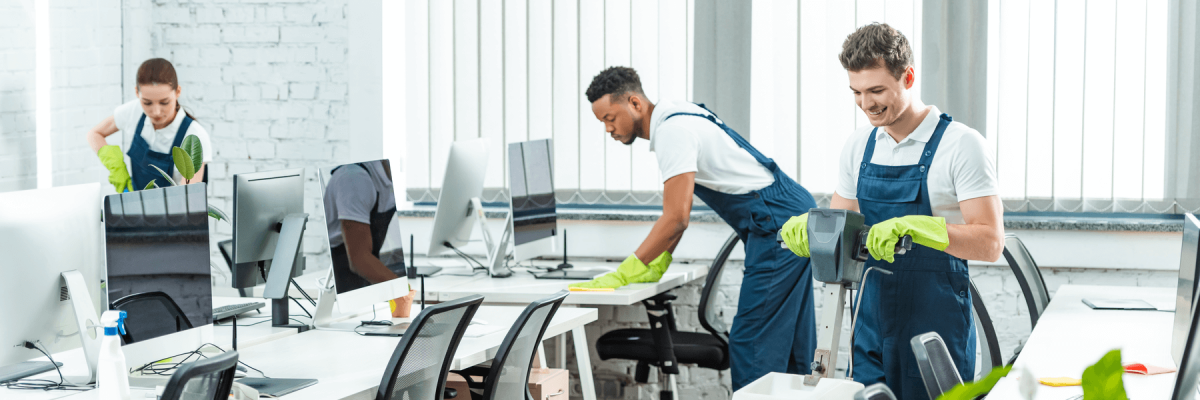 Men and women cleaning a bright office full of computers