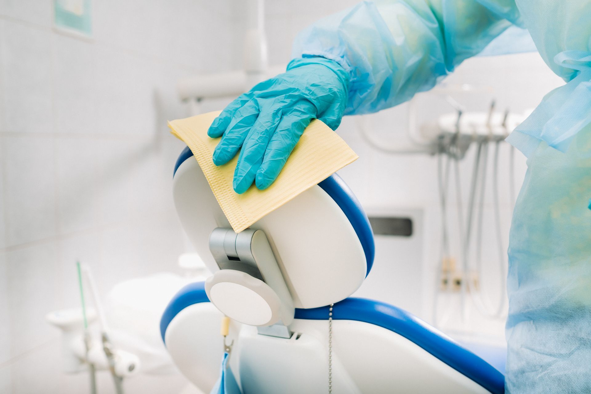 A dentist is cleaning a dental chair with a cloth.