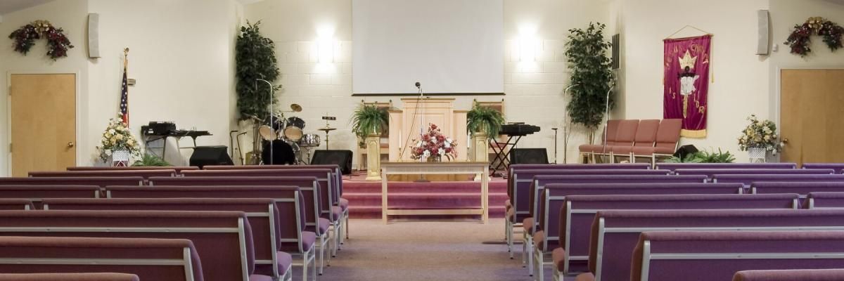 An empty church with purple benches and a projector screen.