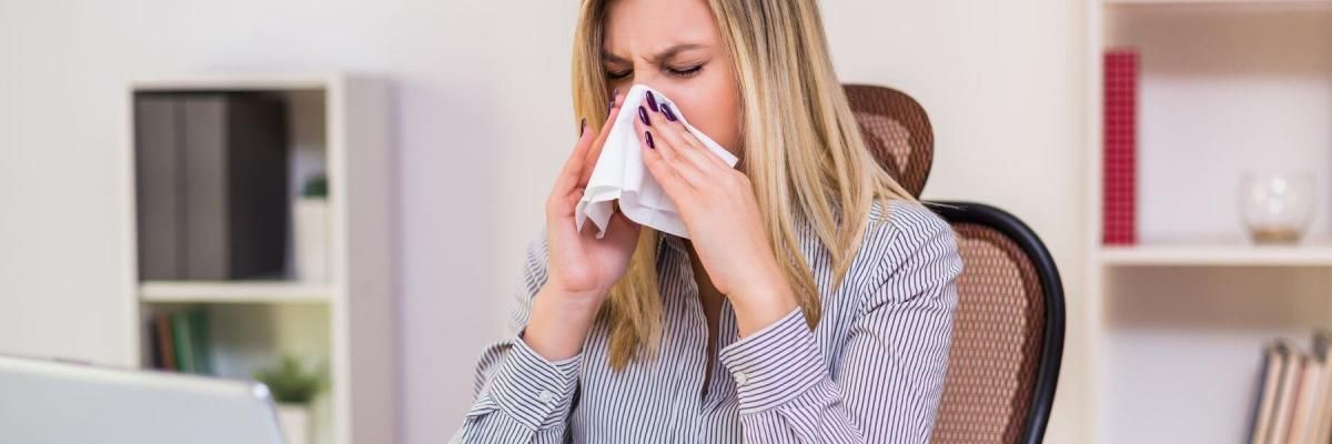 Businesswoman blowing nose while working in her office.