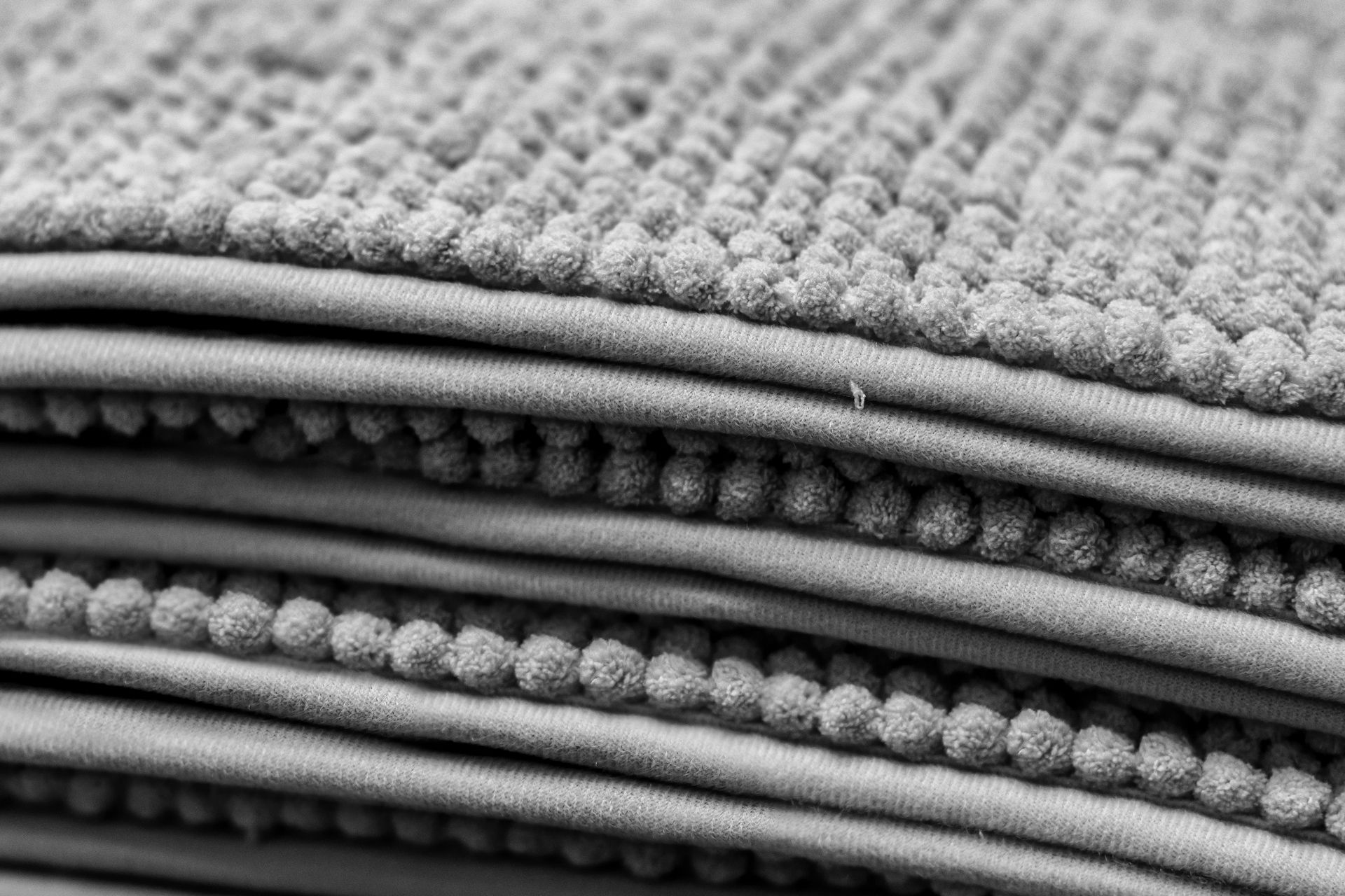 A black and white photo of a stack of bath mats.