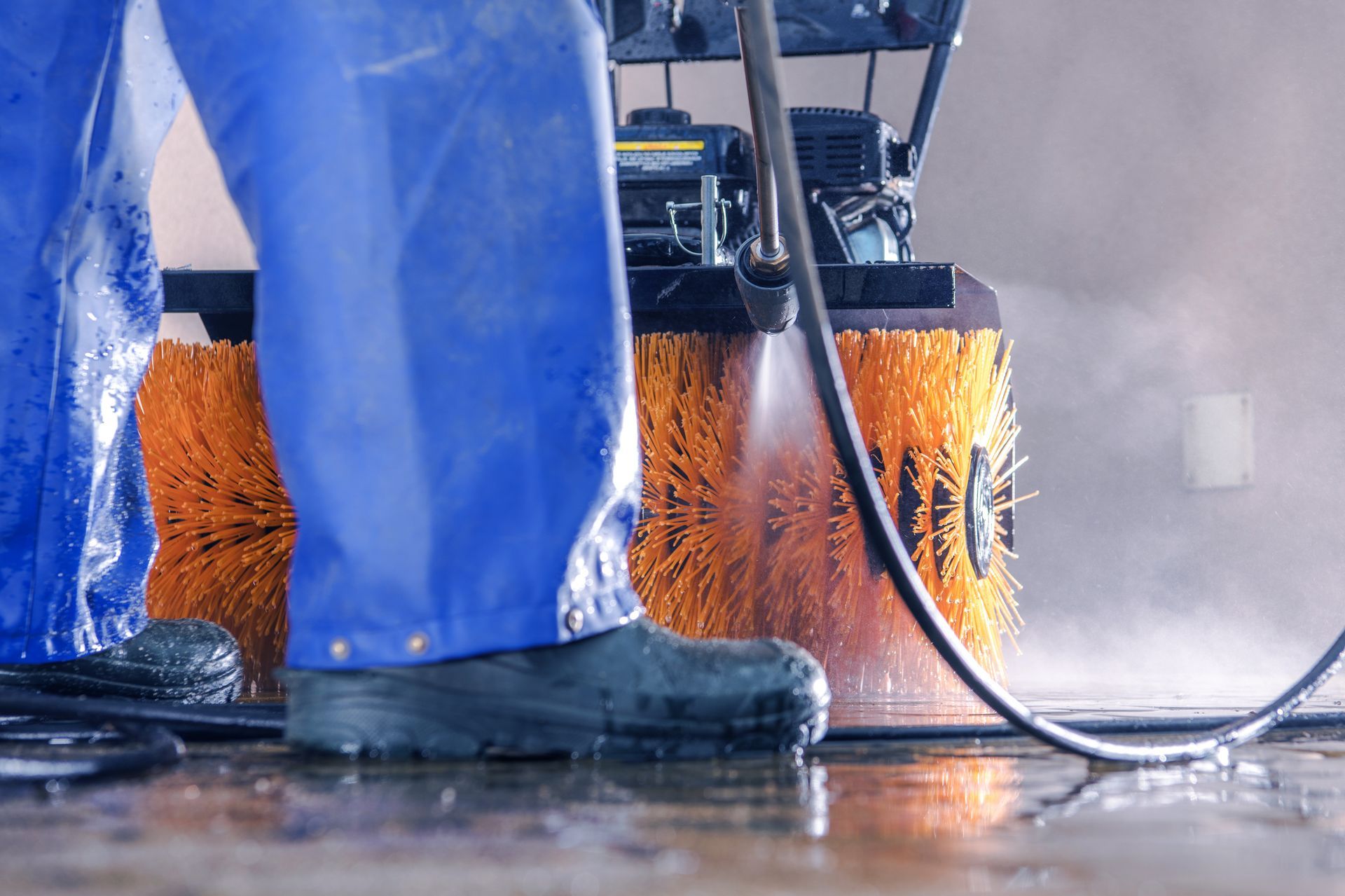 A person is cleaning a floor with a high pressure washer.
