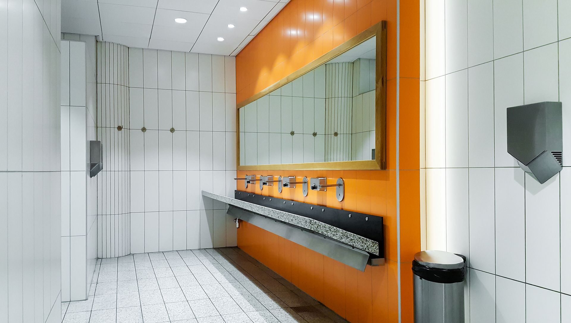 A public restroom with orange walls and white tiles