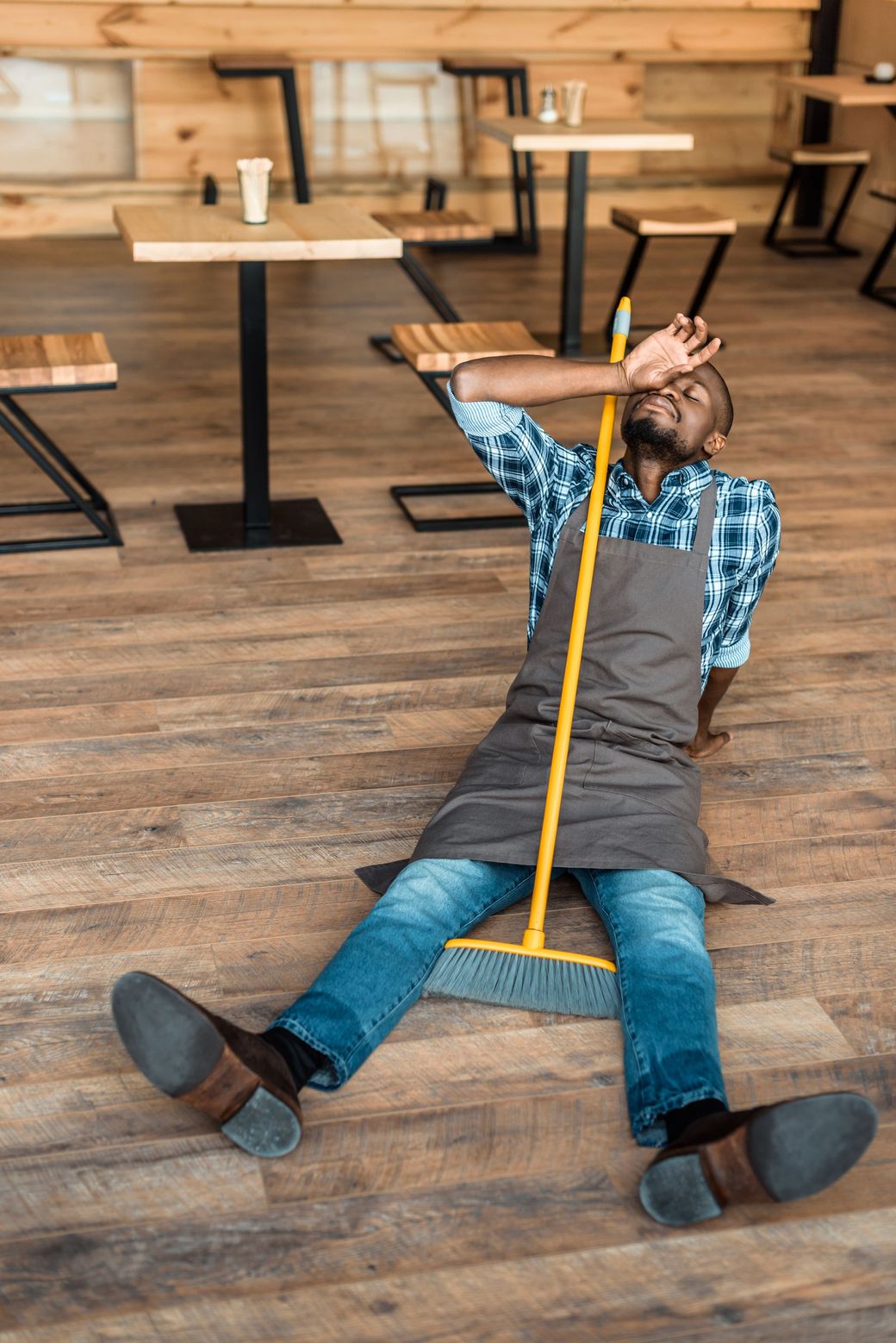 A man is laying on the floor with a mop.