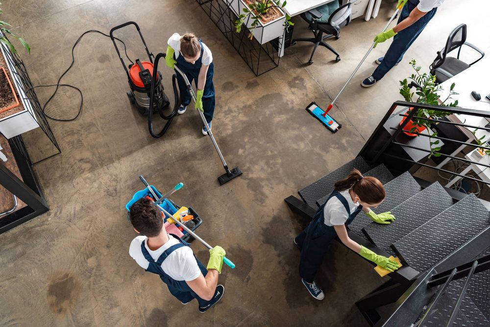 A group of people are cleaning an office with cleaning supplies.