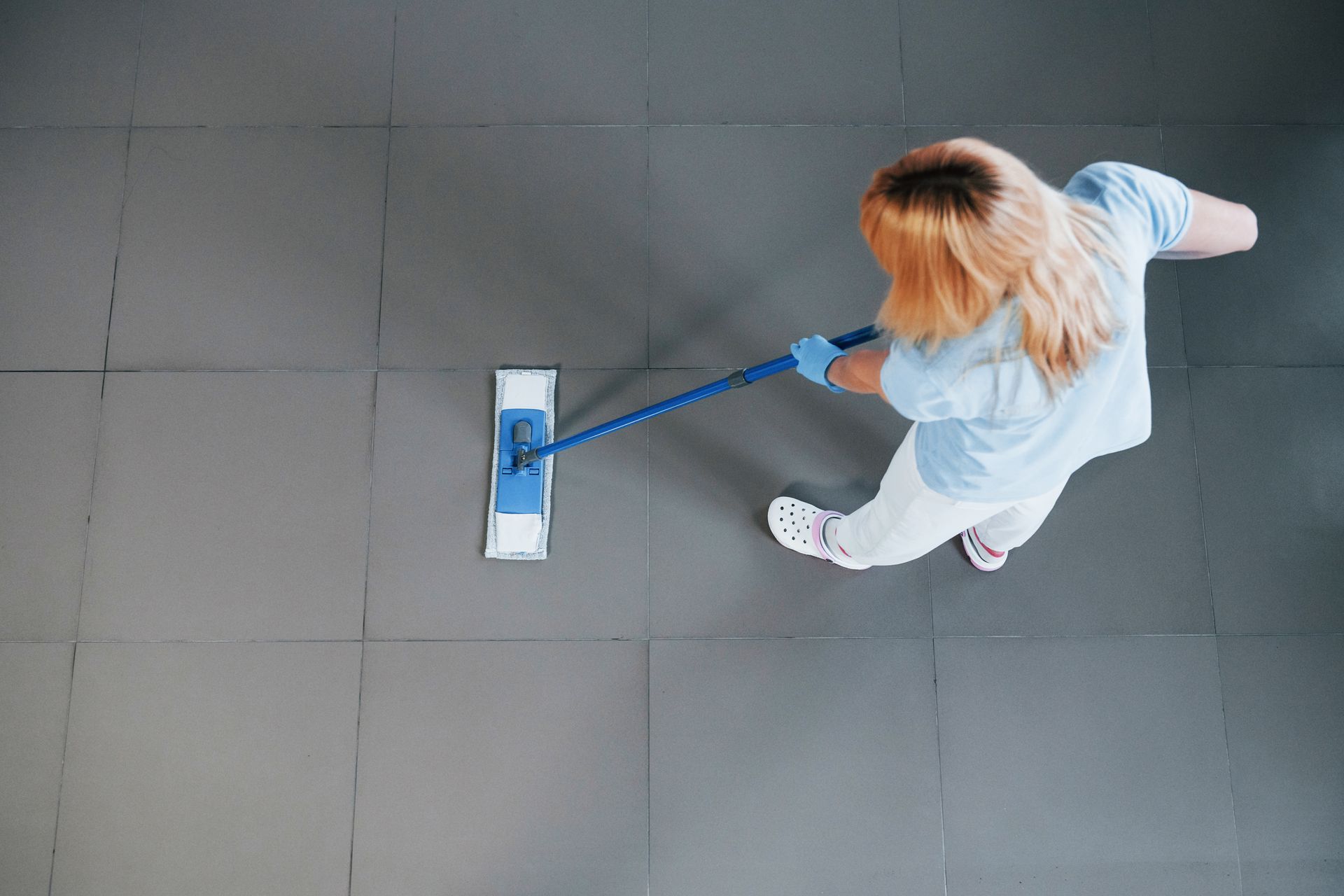 A woman is cleaning the floor with a mop.