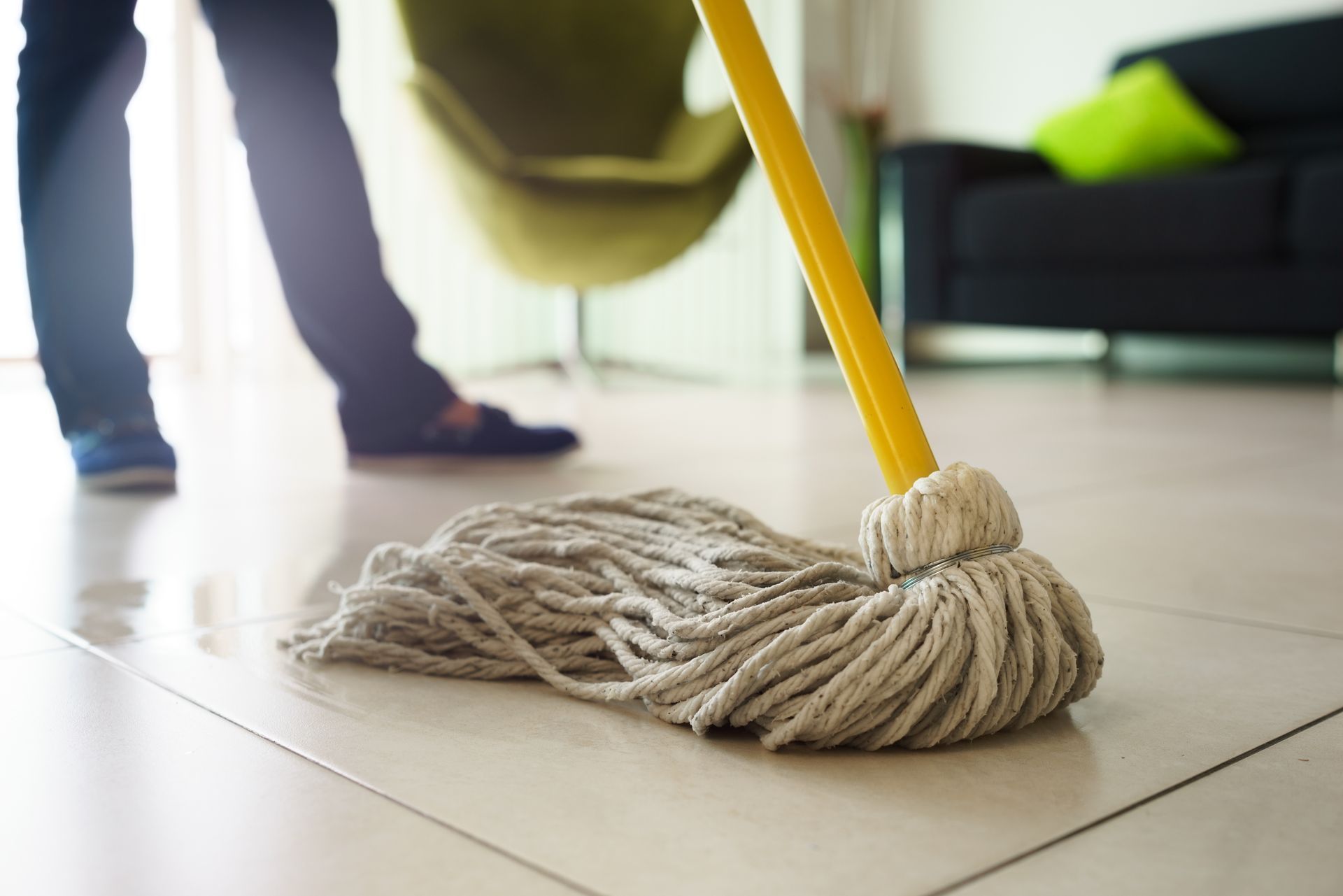 A person is cleaning the floor with a mop in a living room.