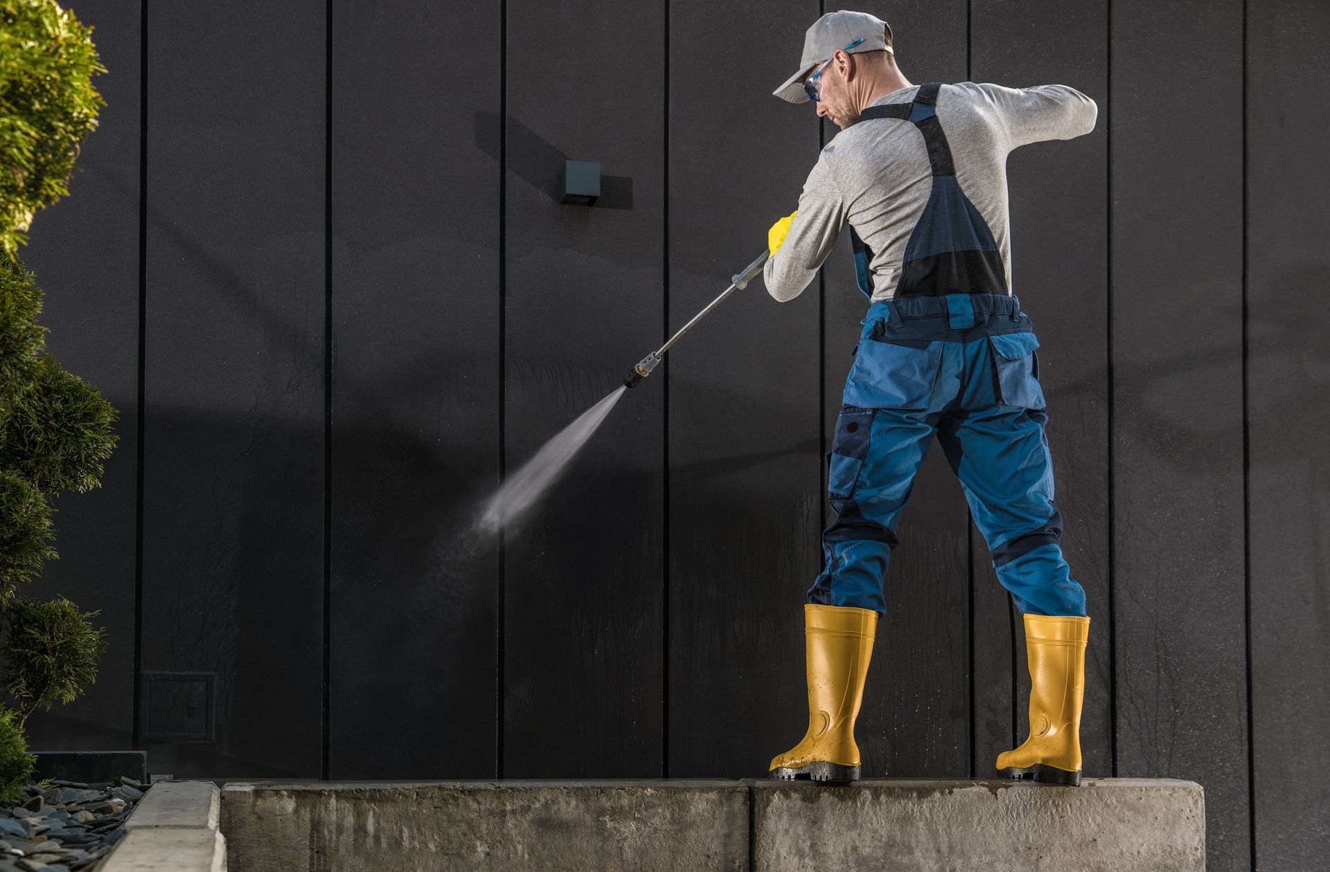 A man is cleaning a wall with a high pressure washer.