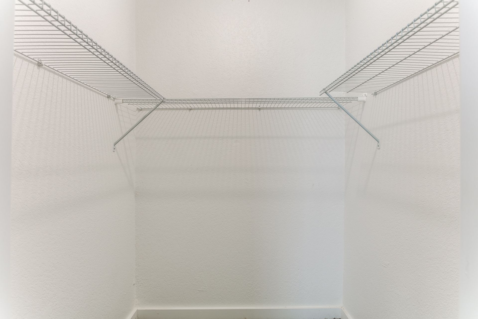 Empty white closet with wire shelving and a clothes rod.