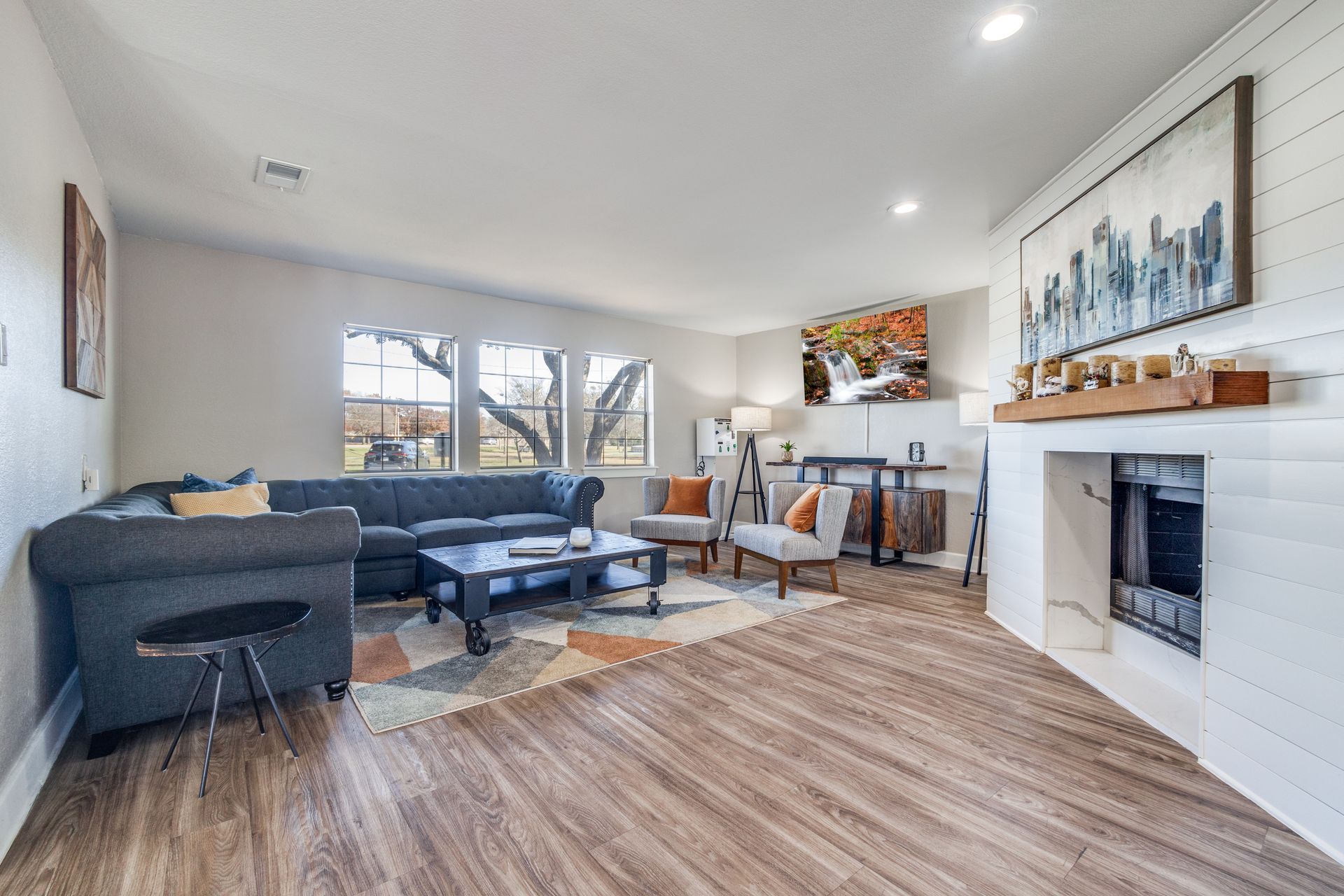 Living room with gray sofa, patterned rug, fireplace, and large painting.