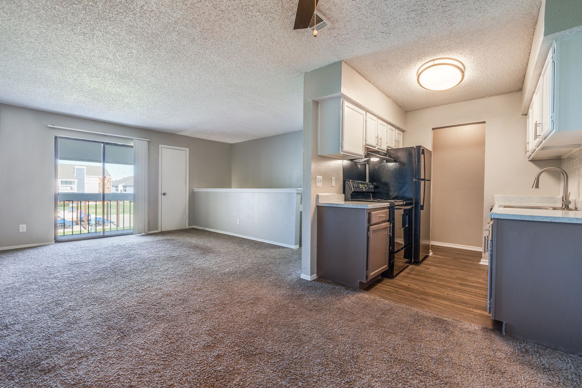 Living room and kitchen with gray walls, carpet, and appliances.