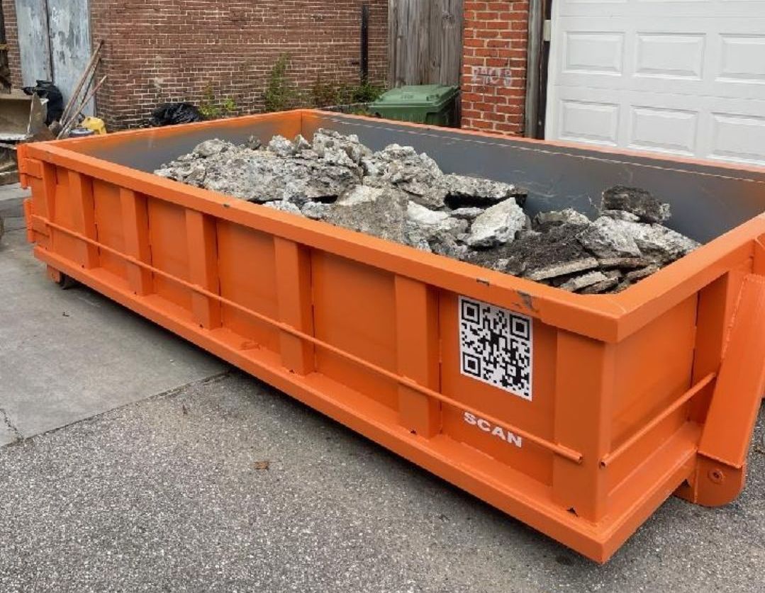 a large orange dumpster is parked next to a black dumpster that says rent