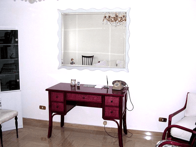 Specchiera con cornice inclinata e ondulata