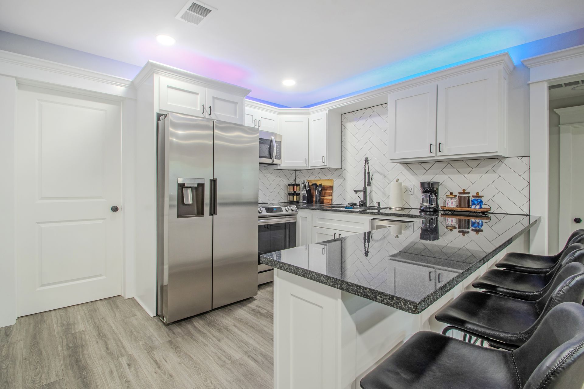 A kitchen with stainless steel appliances , granite counter tops , and white cabinets.
