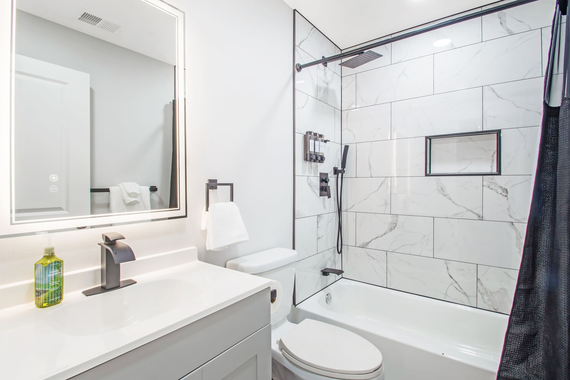 A bathroom with a toilet , sink , shower and mirror.