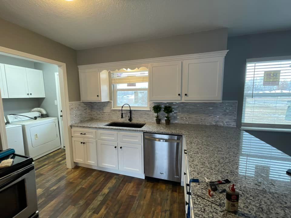 A kitchen with white cabinets , granite counter tops , stainless steel appliances and a sink.