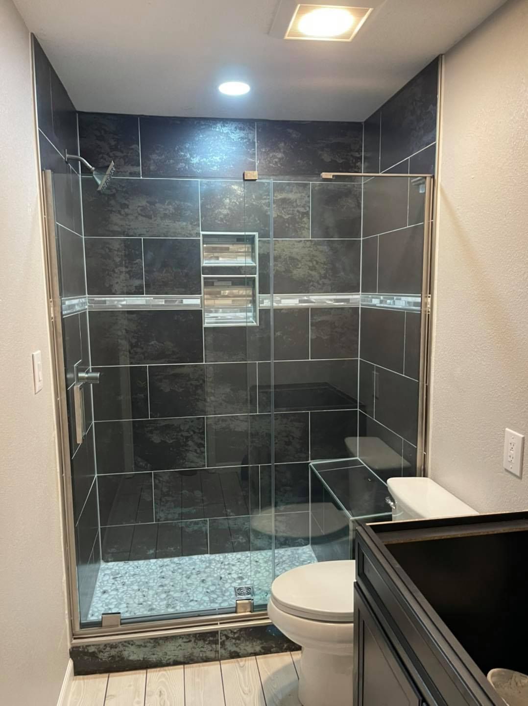 A bathroom with a toilet and a walk in shower with a glass door.