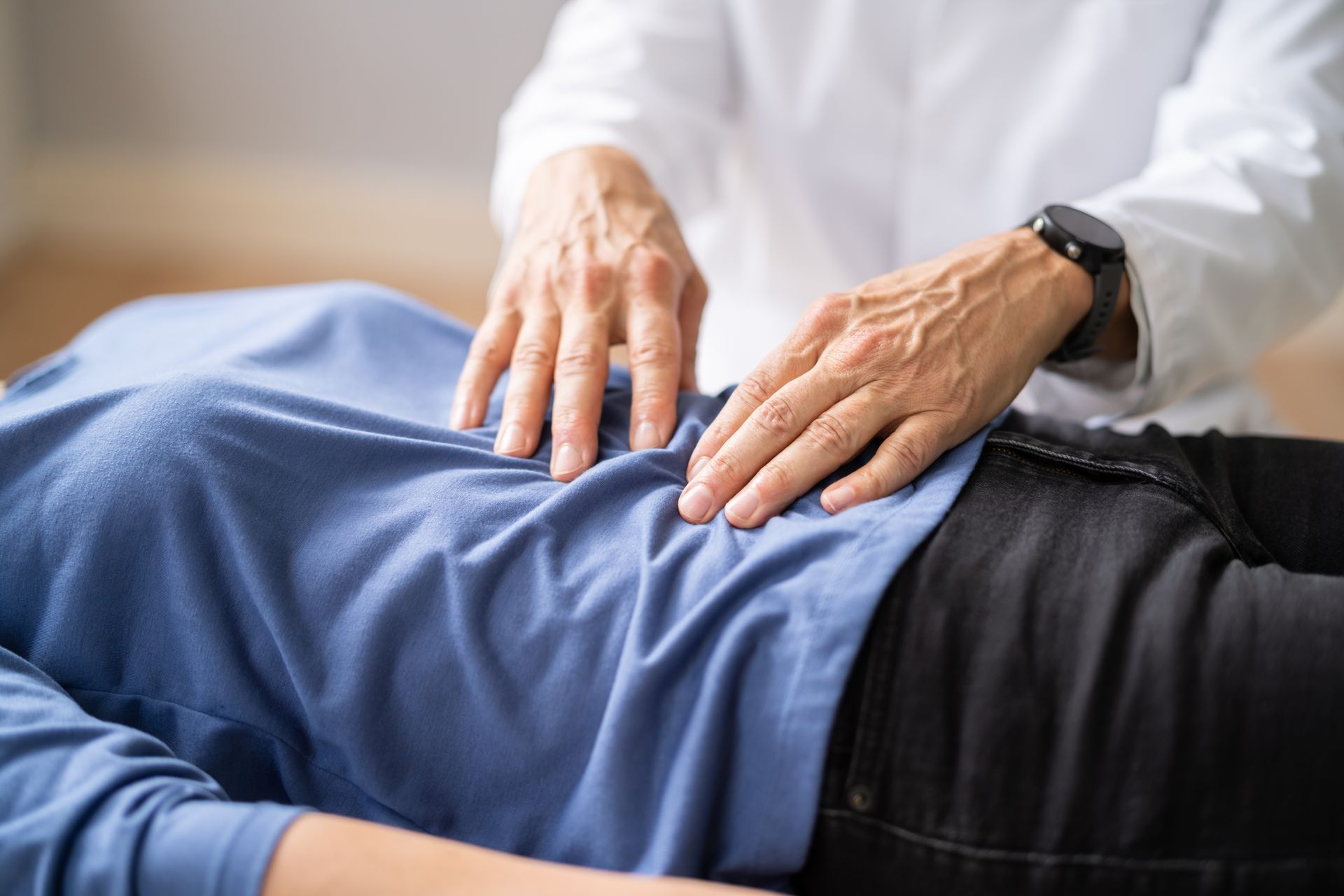 A doctor is examining a woman 's stomach with his hands.