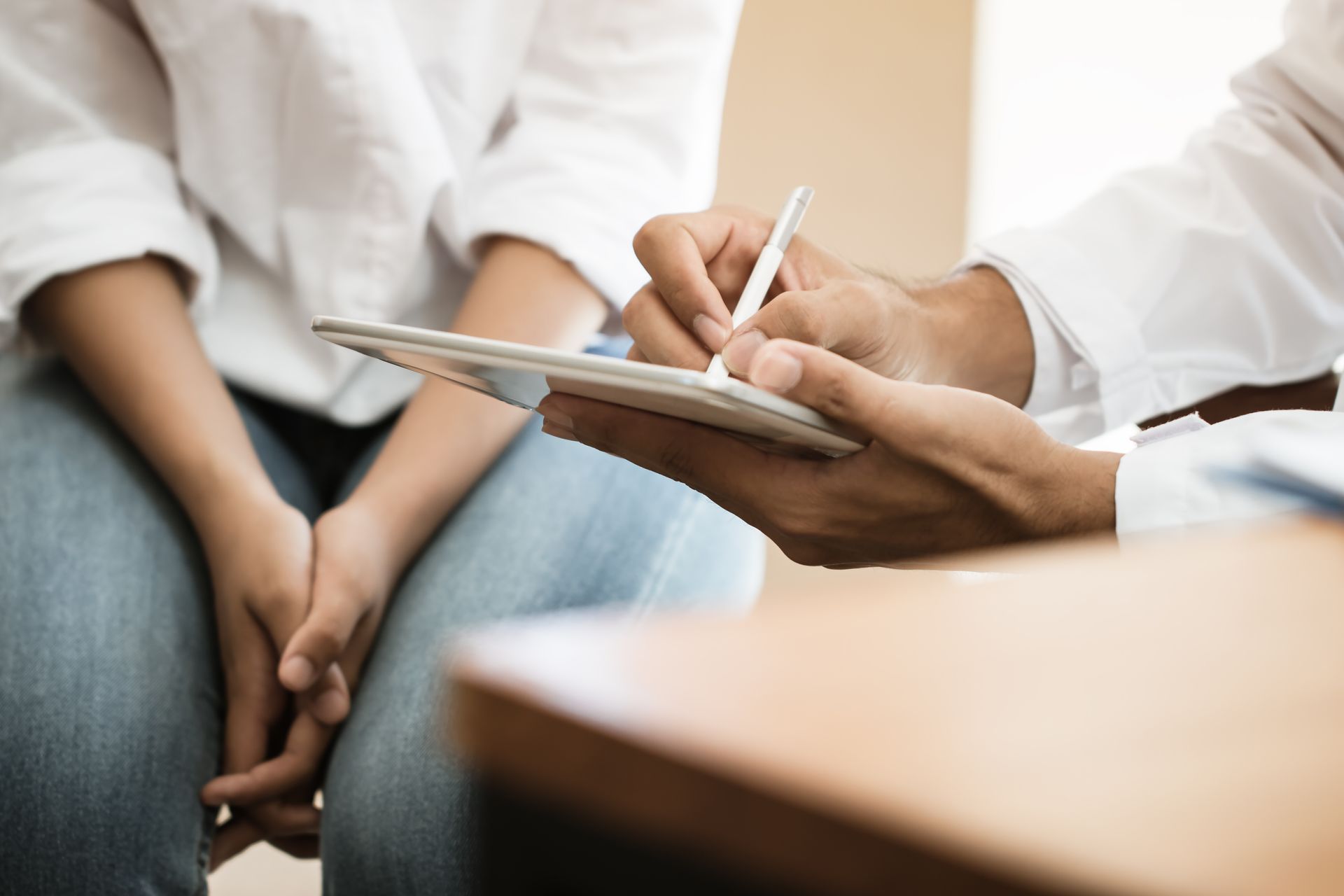 A doctor is taking notes on a clipboard while talking to a patient.