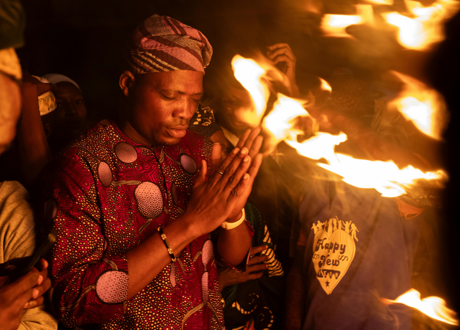 Man in traditional attire praying near flames, celebrating a new year.