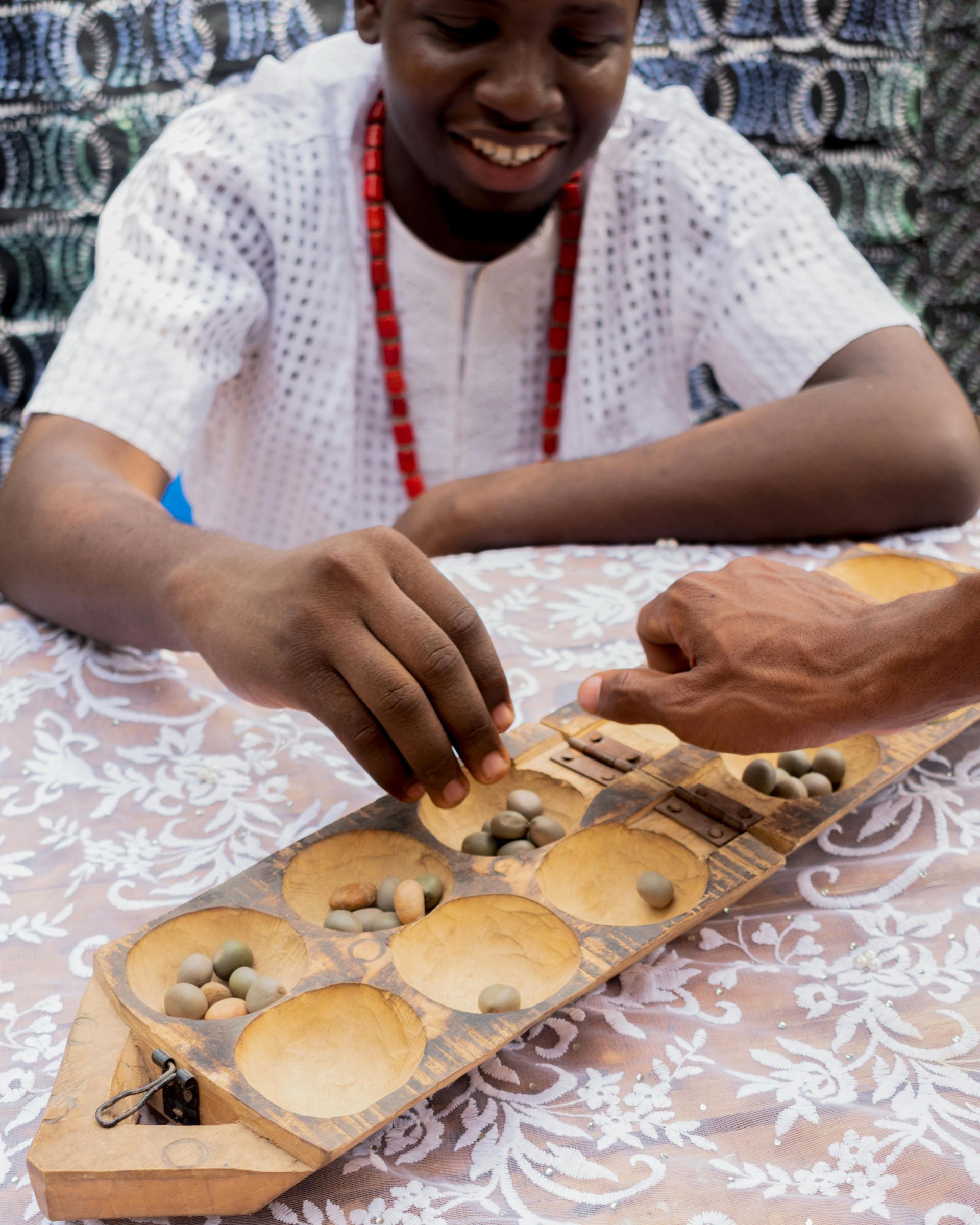 Man and person play a board game, smiling. Wooden game board with stones, on a table.
