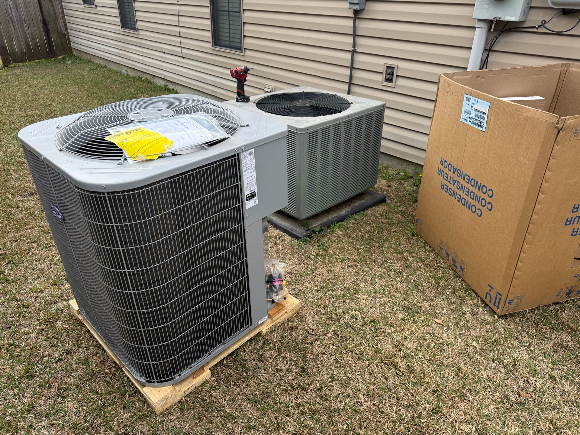 HVAC unit on a pallet outside a building. Brown cardboard box nearby.