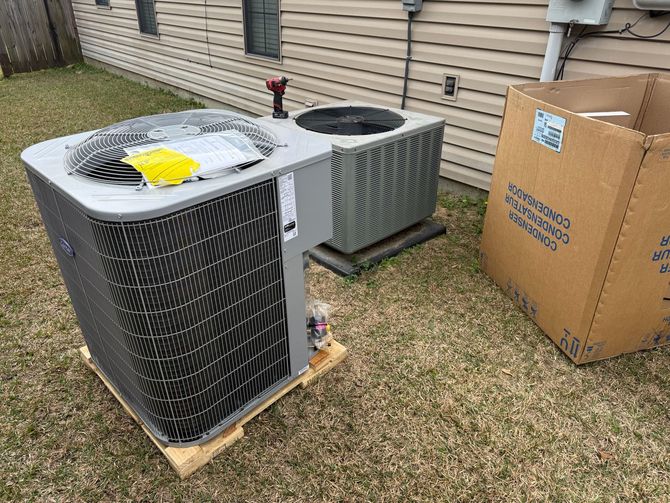 HVAC unit on a pallet outside a building. Brown cardboard box nearby.