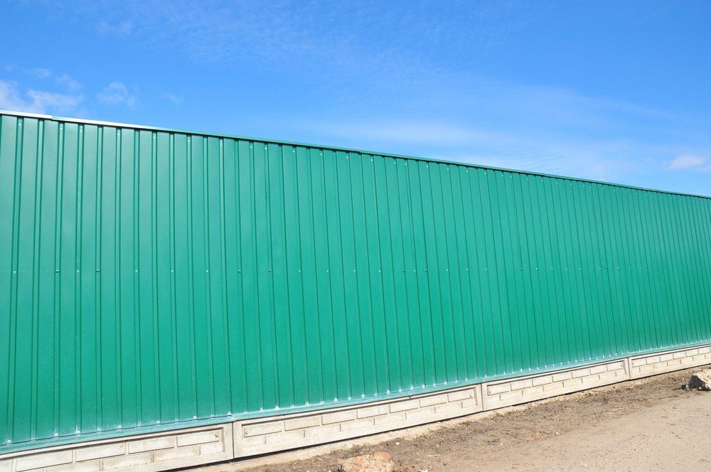 Green Corrugated Metal Fence Against a Blue Sky — Capital Fencing in Tuggeranong, ACT