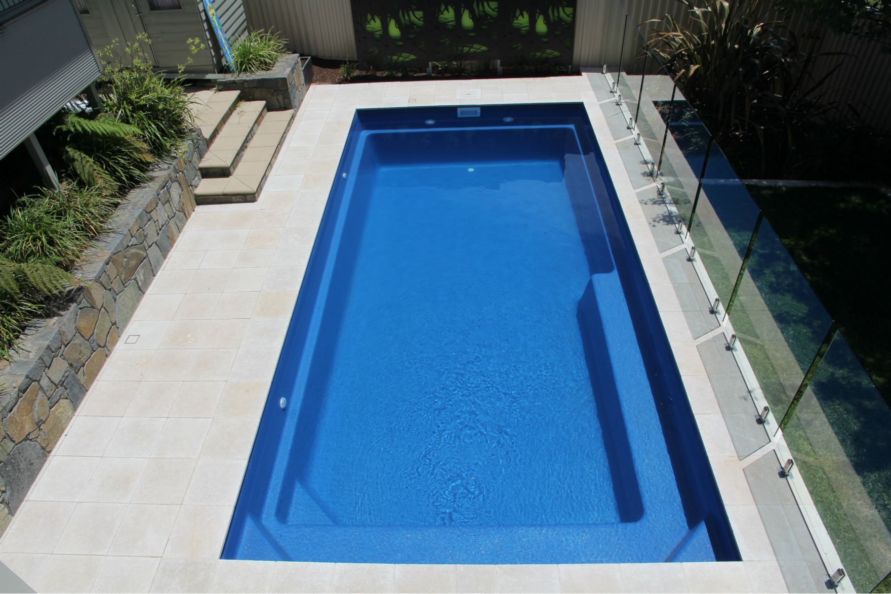 Glass Pool Fencing Surrounding a Blue Pool   — Capital Fencing in Charnwood, ACT