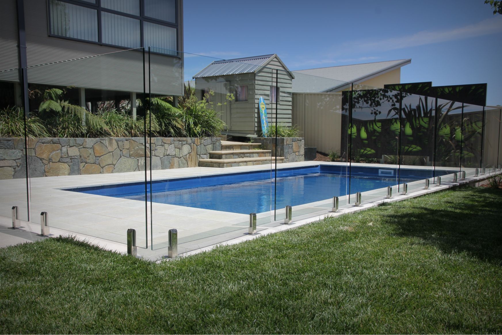 Swimming Pool With a Glass Fence In A Backyard — Capital Fencing in Charnwood, ACT