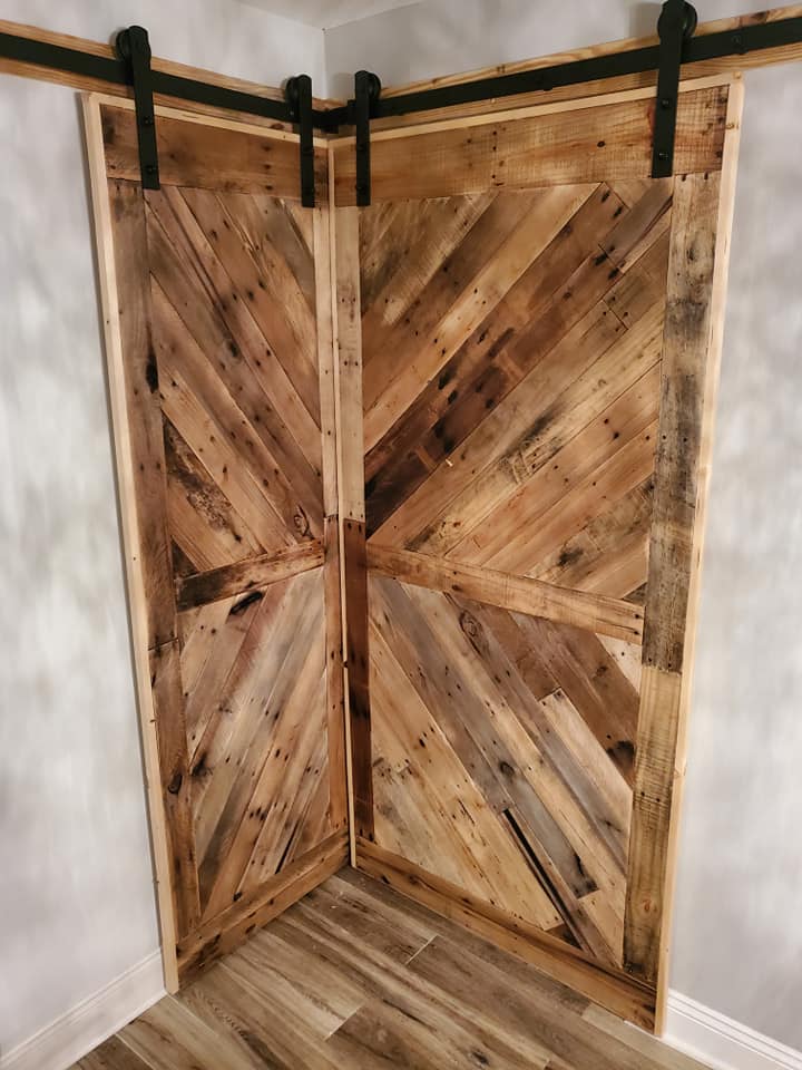 Rustic, corner sliding barn doors made of reclaimed wood, with black hardware.