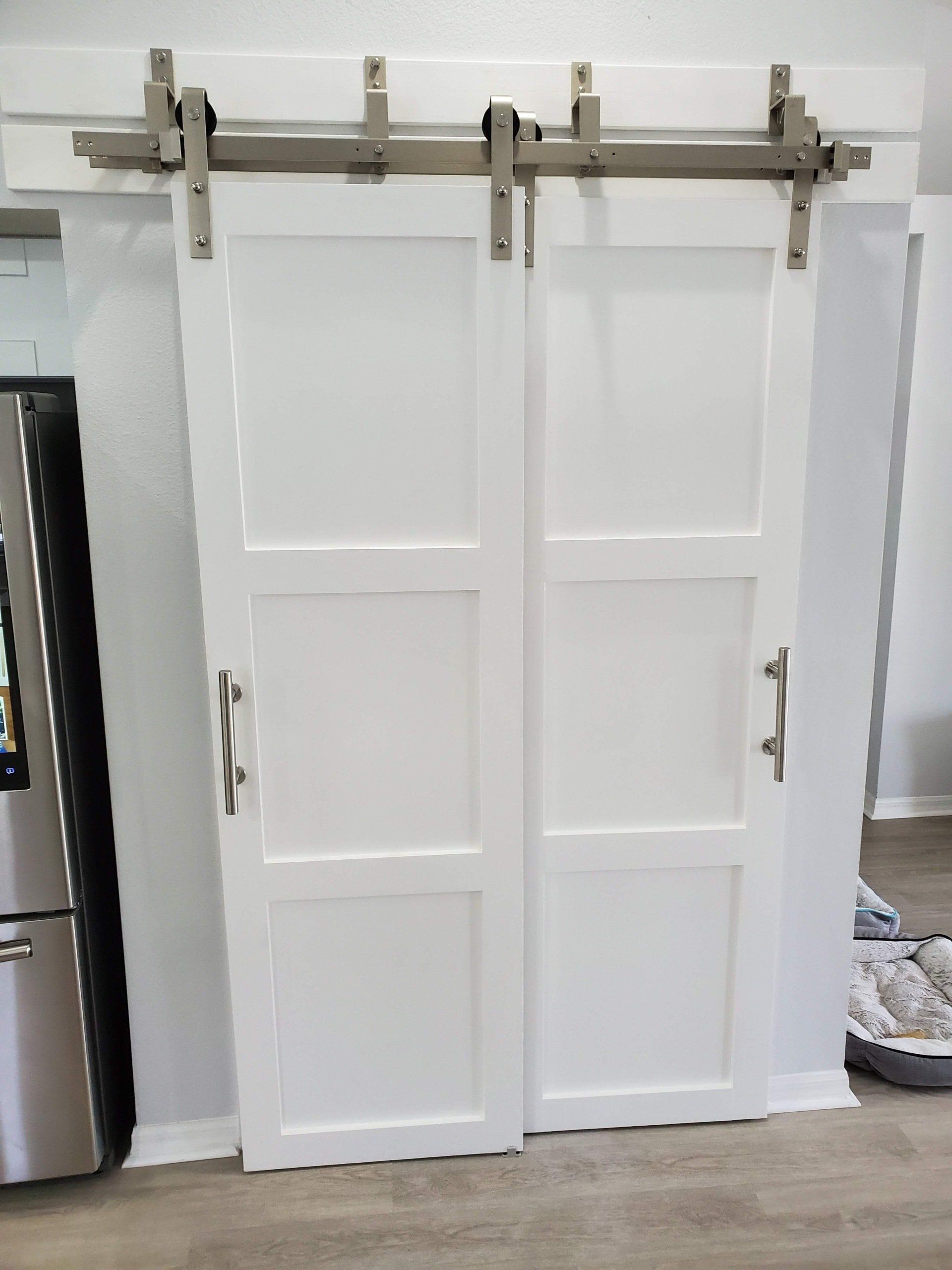 White double sliding barn doors with silver hardware, in a home interior.