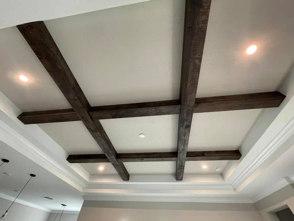 Ceiling with dark brown wooden beams and recessed lighting.
