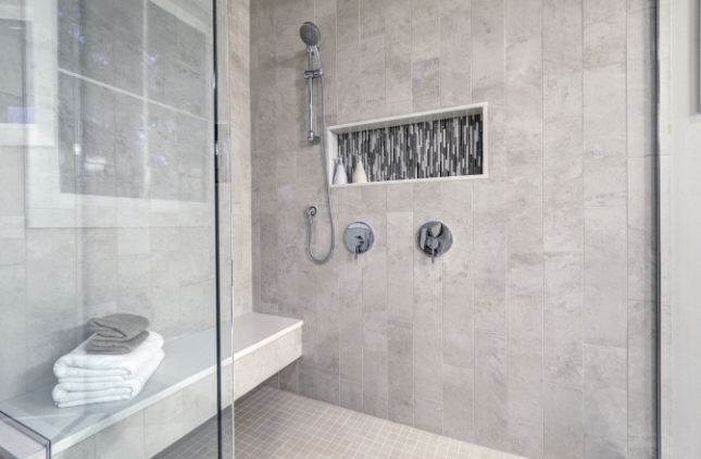 Modern bathroom with a white tub, vanity, and wood-look flooring. Mirrors and lights above the double sinks.