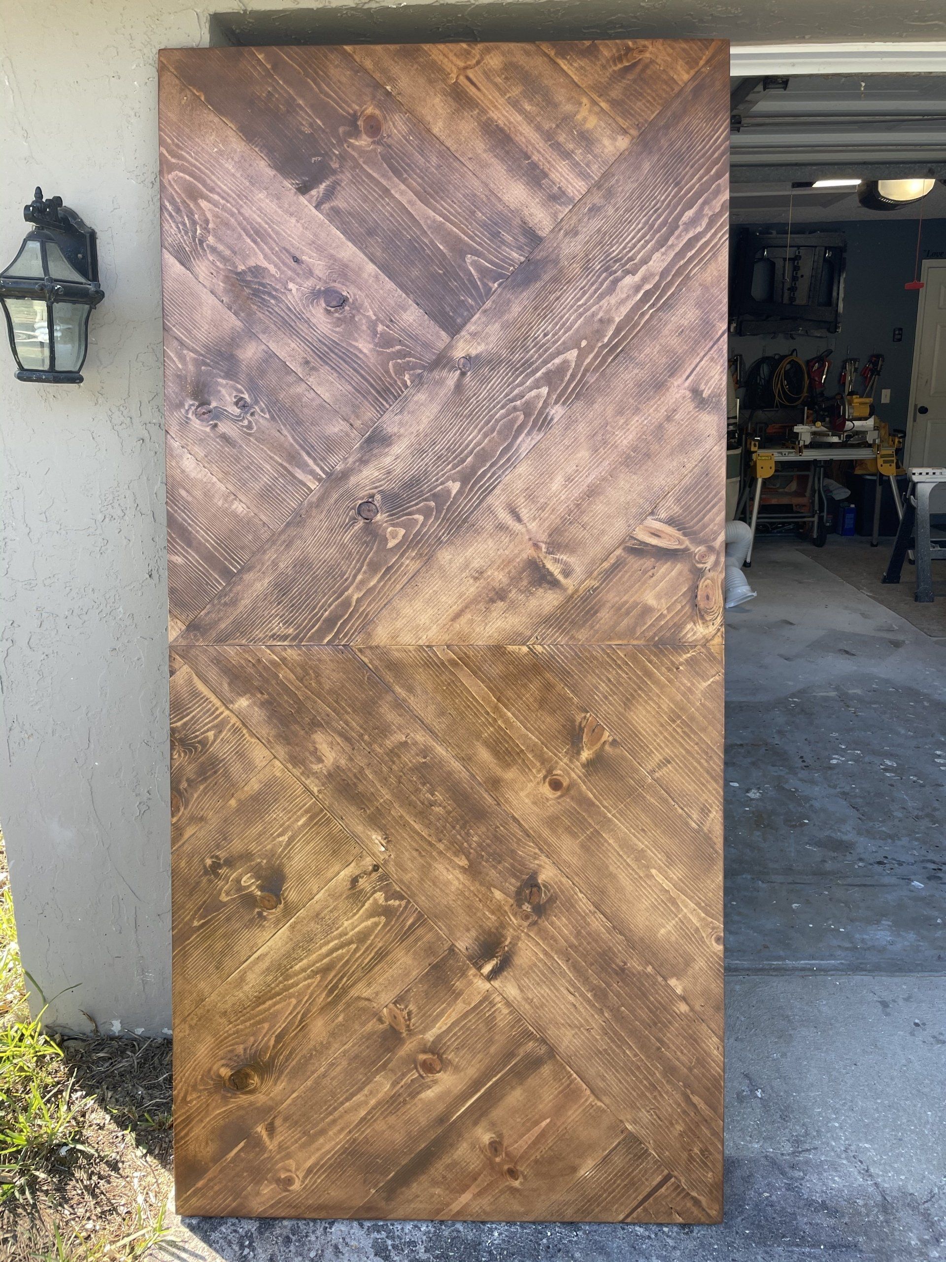 Wooden door with a herringbone pattern, stained in shades of brown.
