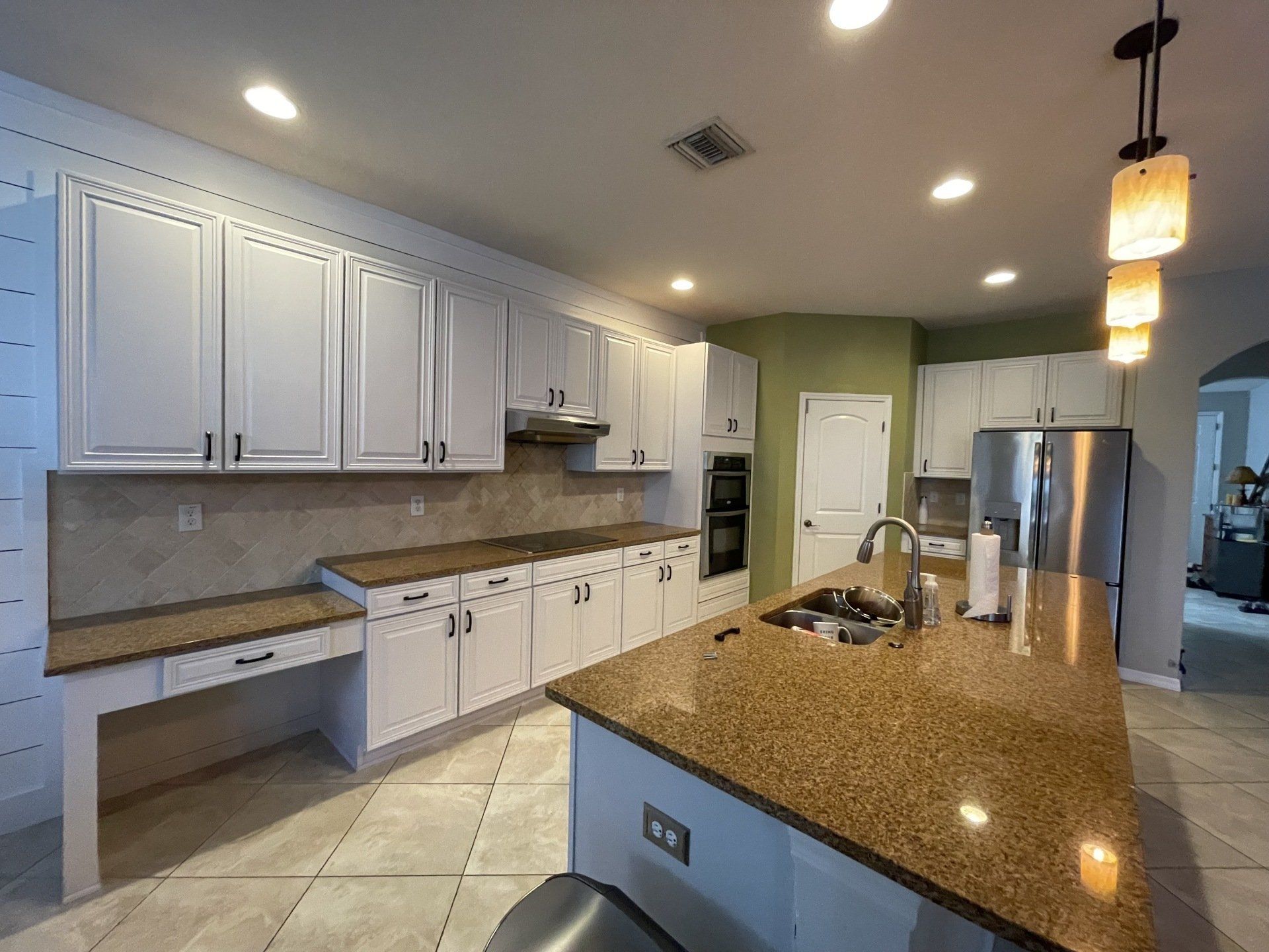 Bright kitchen with white cabinets, granite countertops, and a large island.