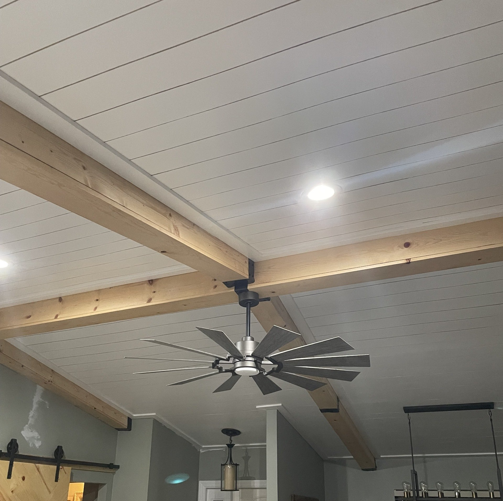 White plank ceiling with wooden beams, a fan, and recessed lighting.