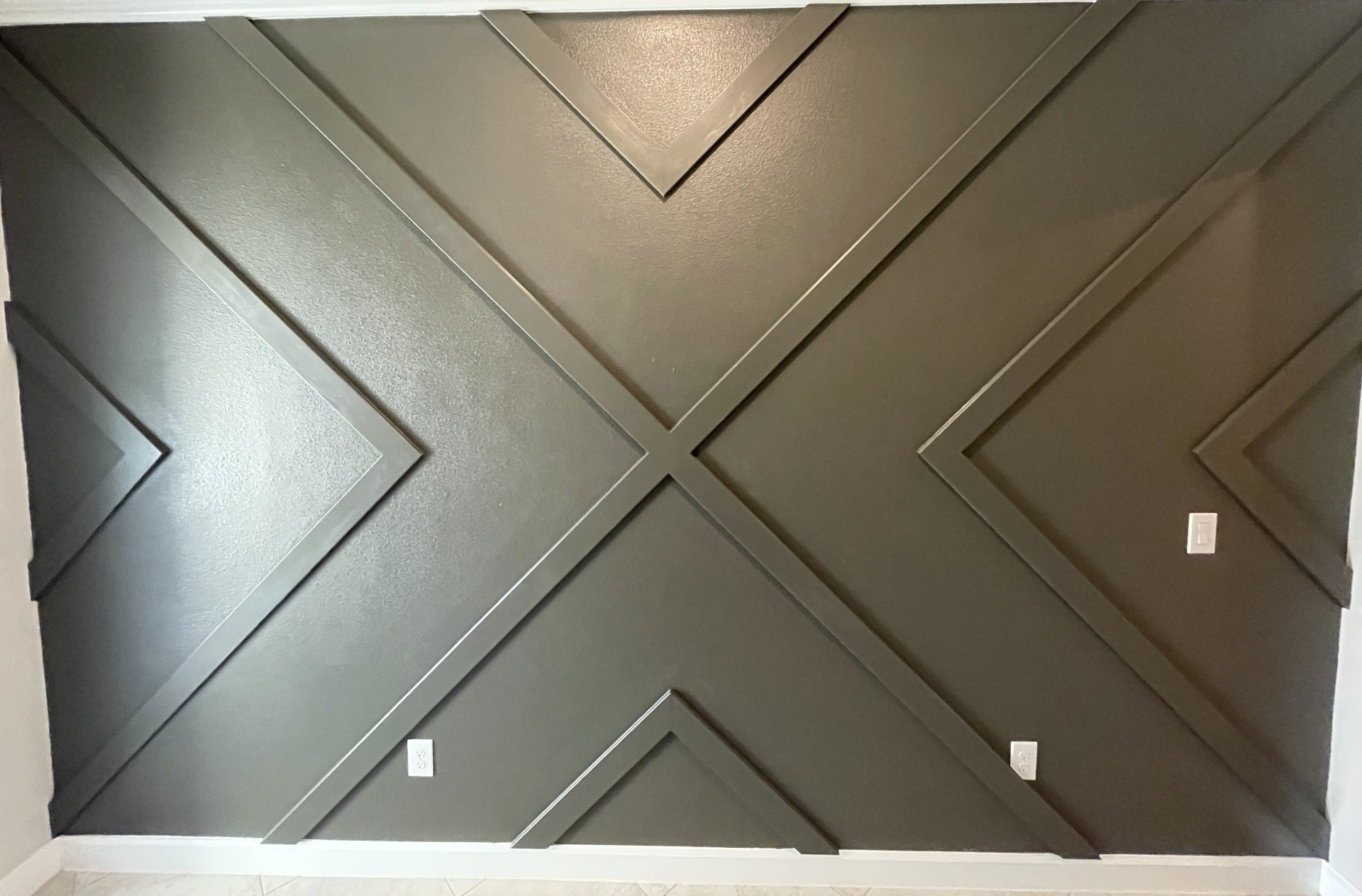 Gray geometric wood trim accent wall with power outlets.
