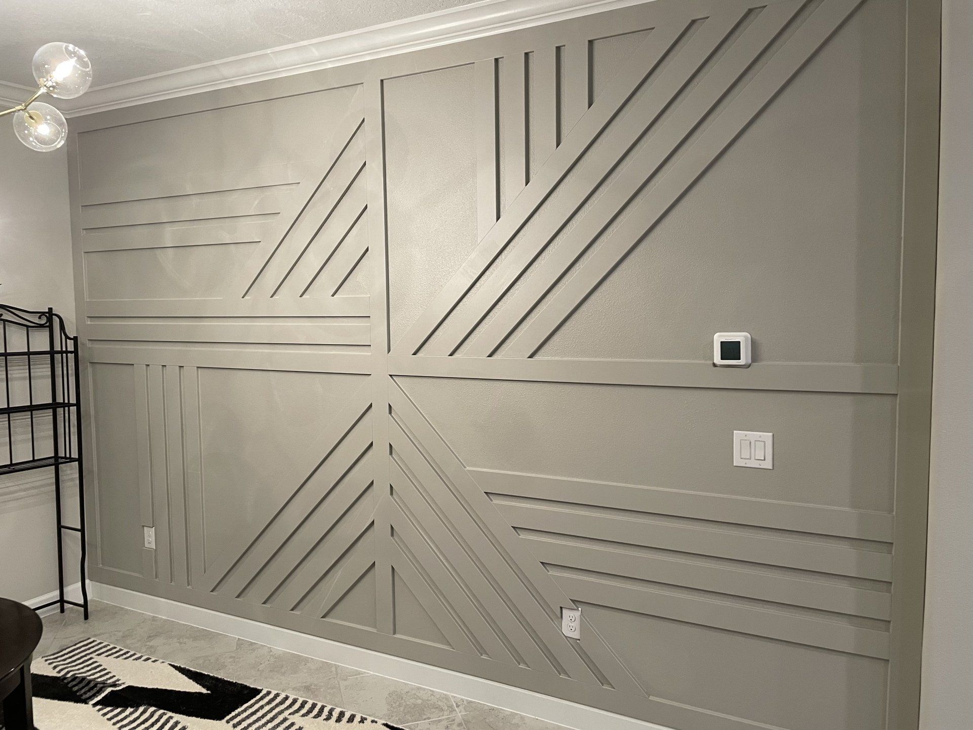 Gray accent wall with geometric wood panel design.