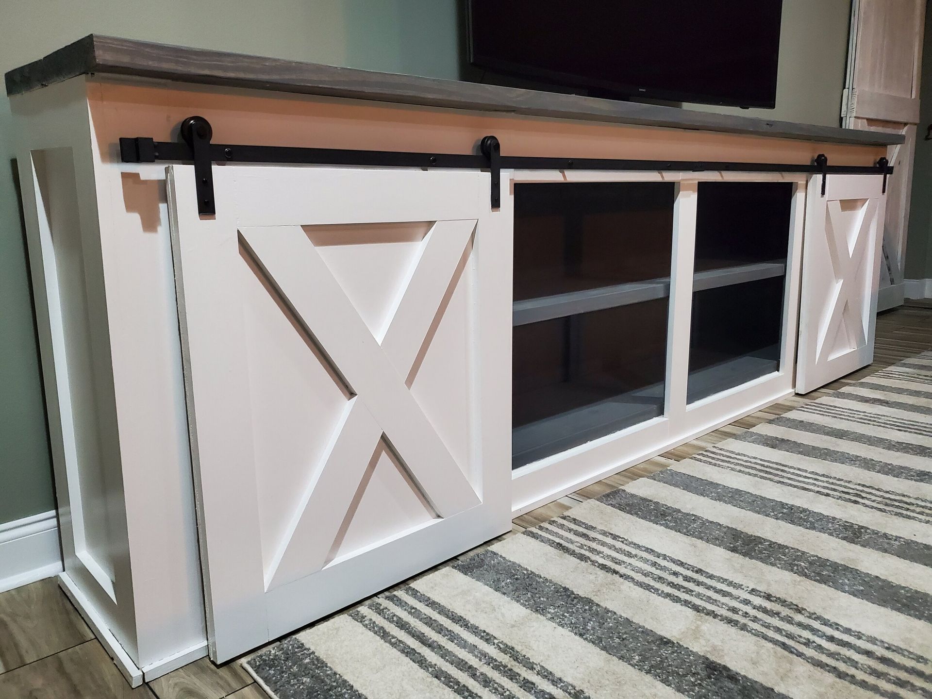 Wooden cabinet with barn doors, gray top, and open shelves.