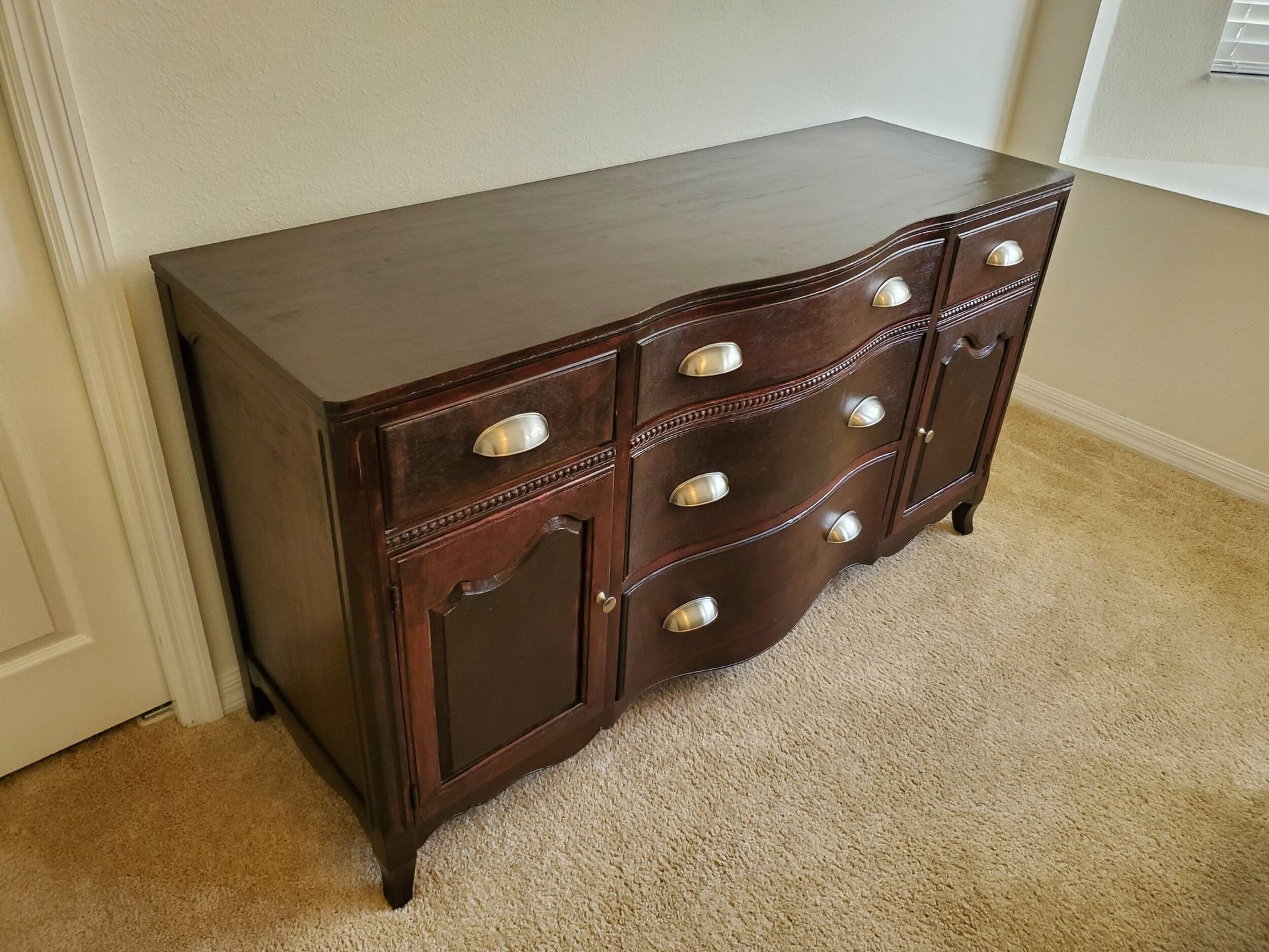 Dark wood sideboard with drawers and cabinets on carpet.