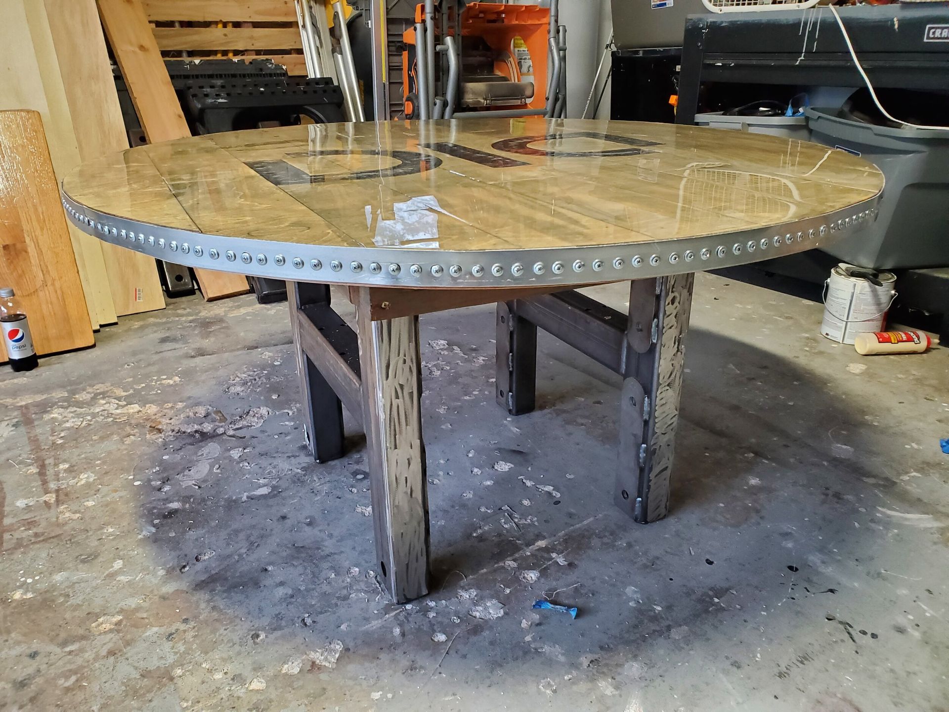 Wooden table with a metal-banded rim and wooden legs, set in a workshop.