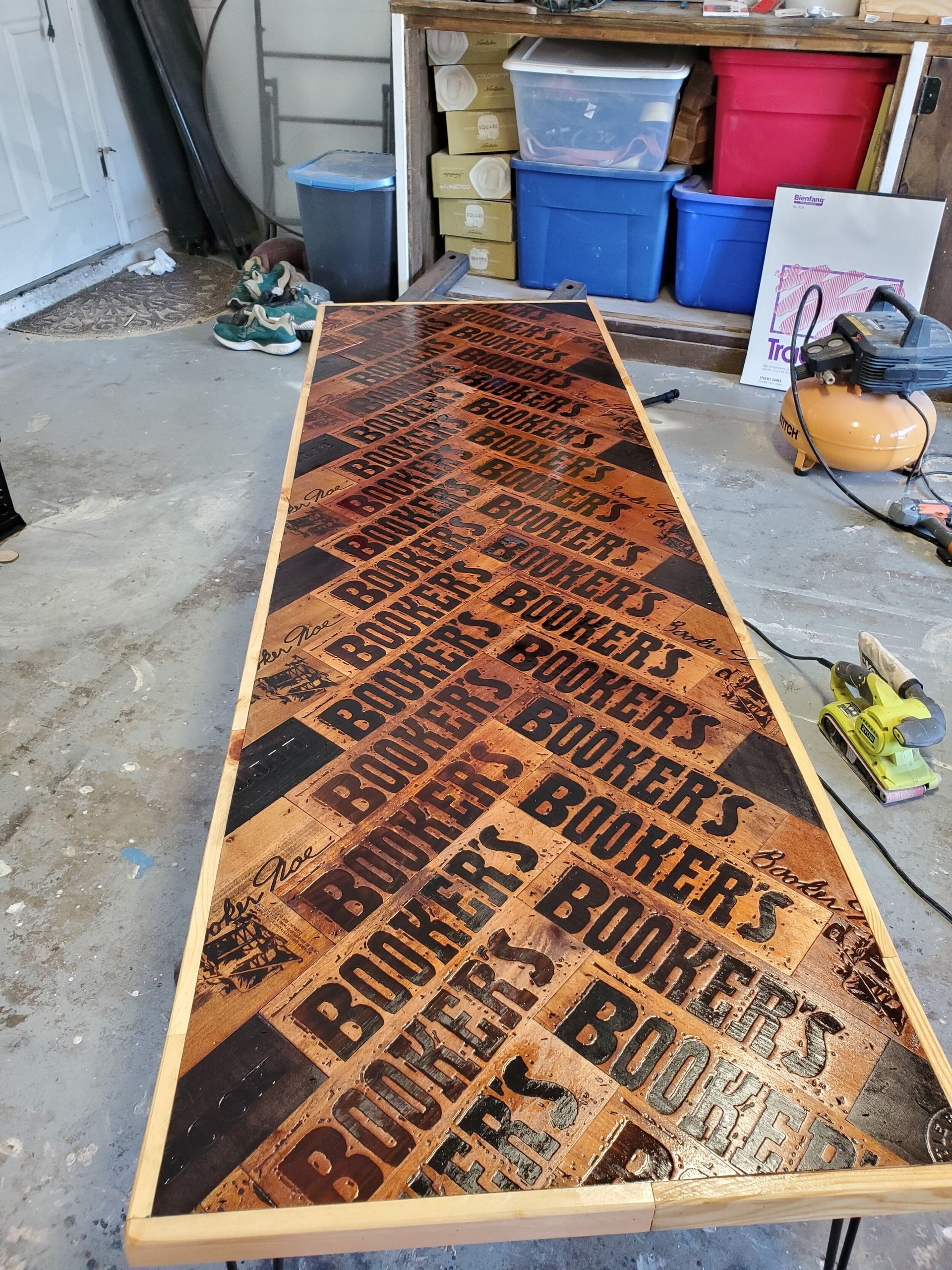 A long table with a whiskey logo pattern. The table is in a garage setting.