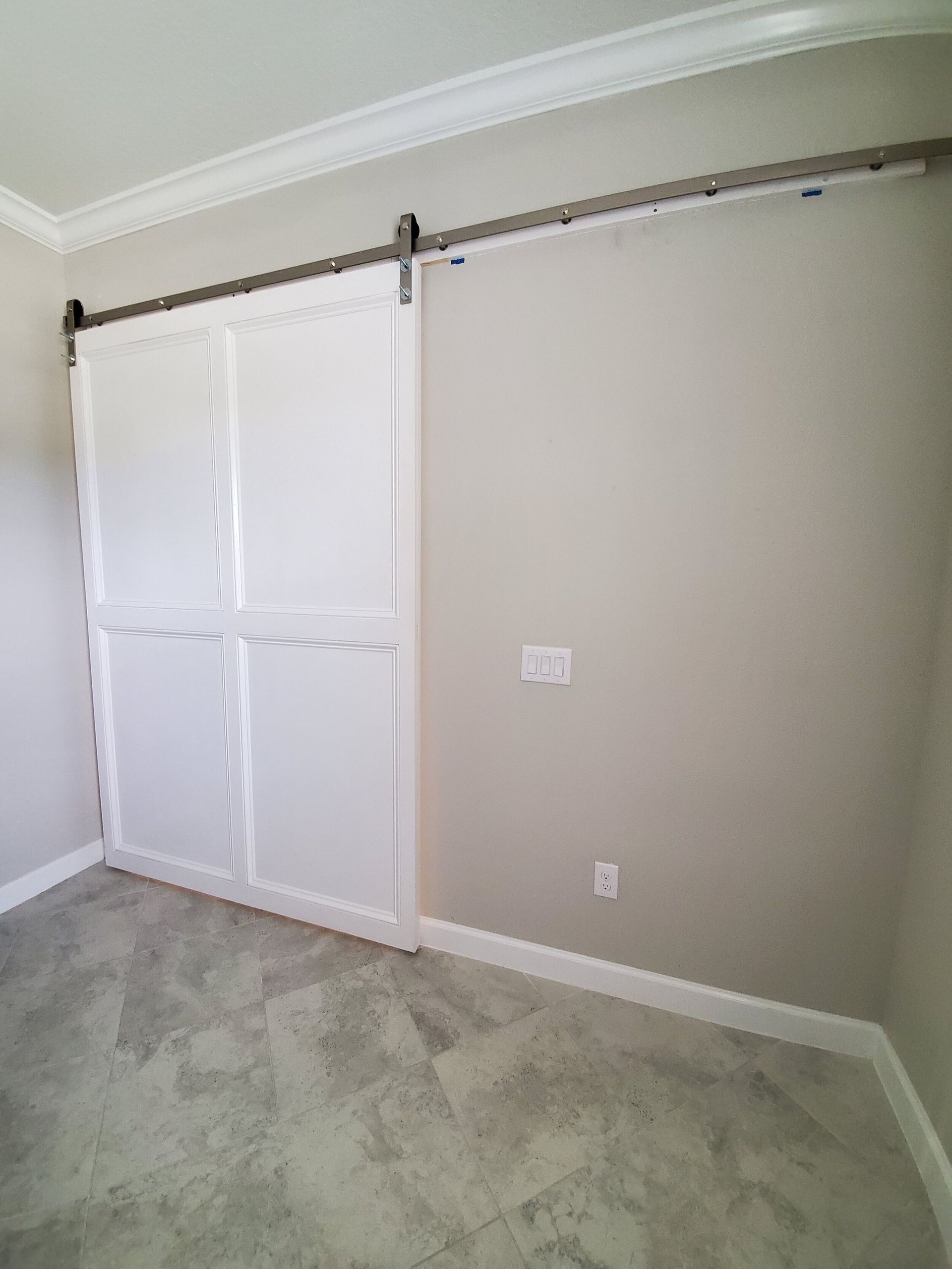 White sliding barn doors over a closet, mounted on a metal track against a beige wall.