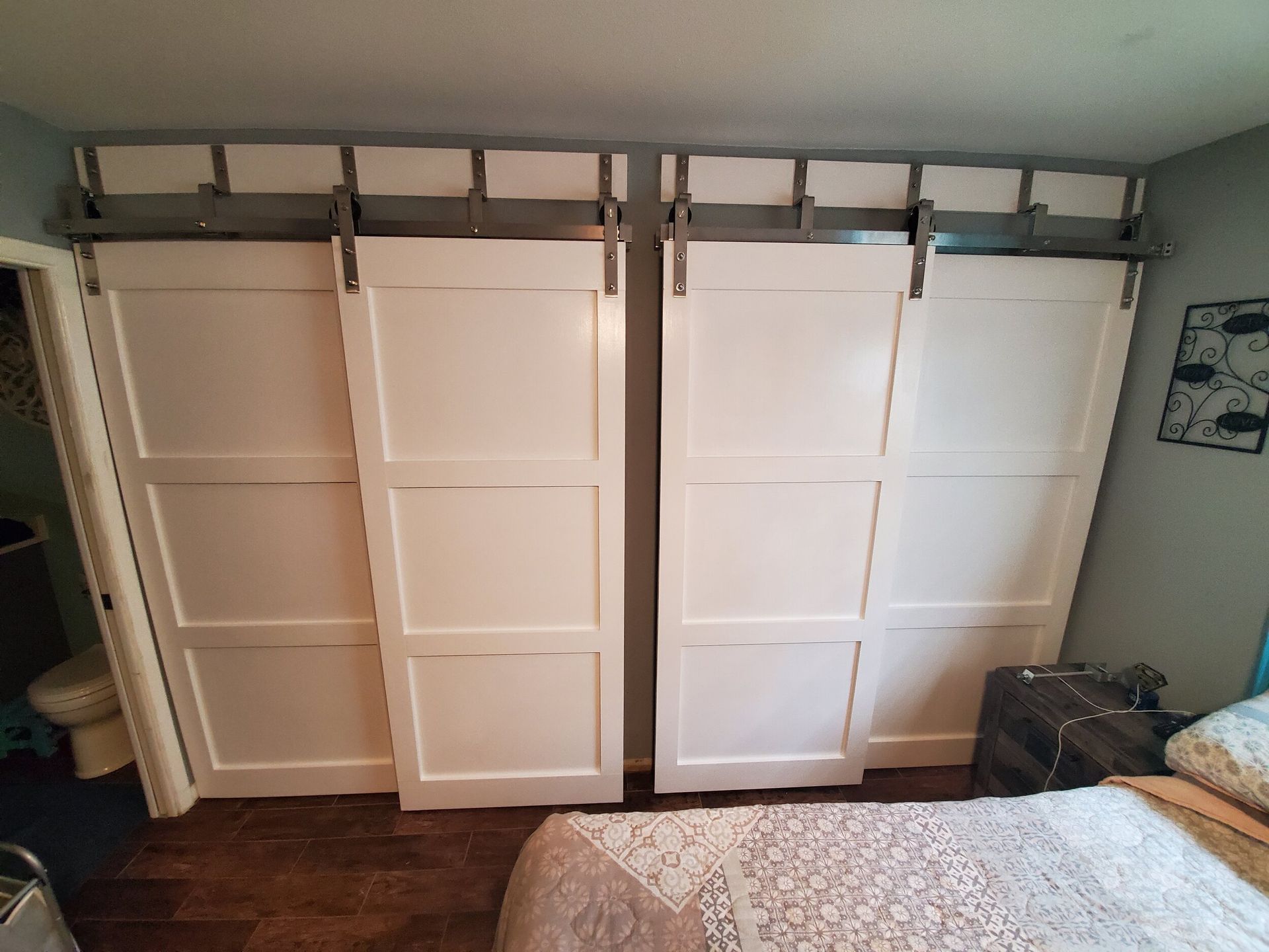 White sliding barn doors on a bedroom closet, mounted on metal tracks.