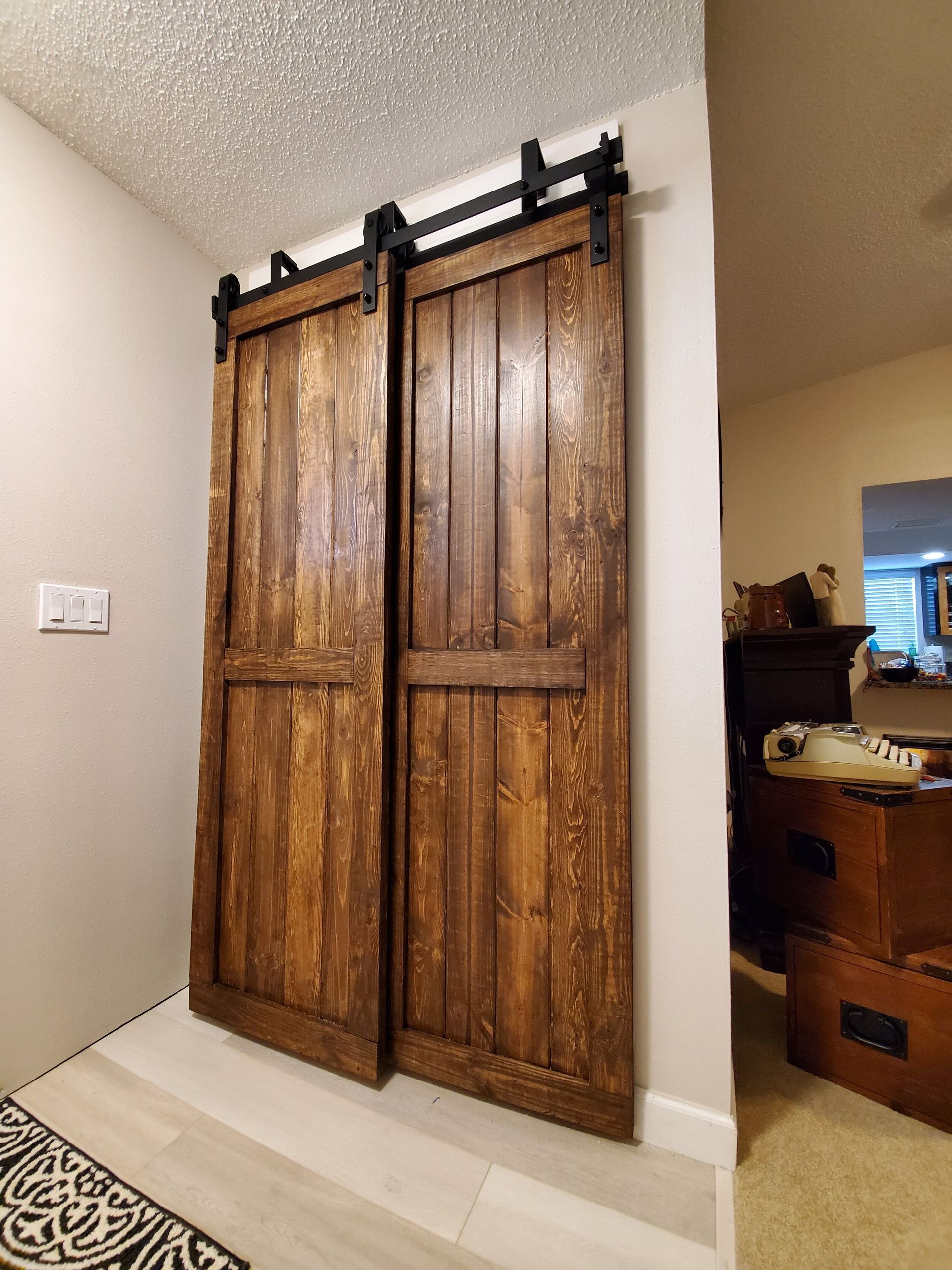 Two rustic wooden sliding doors on a track in an entryway.