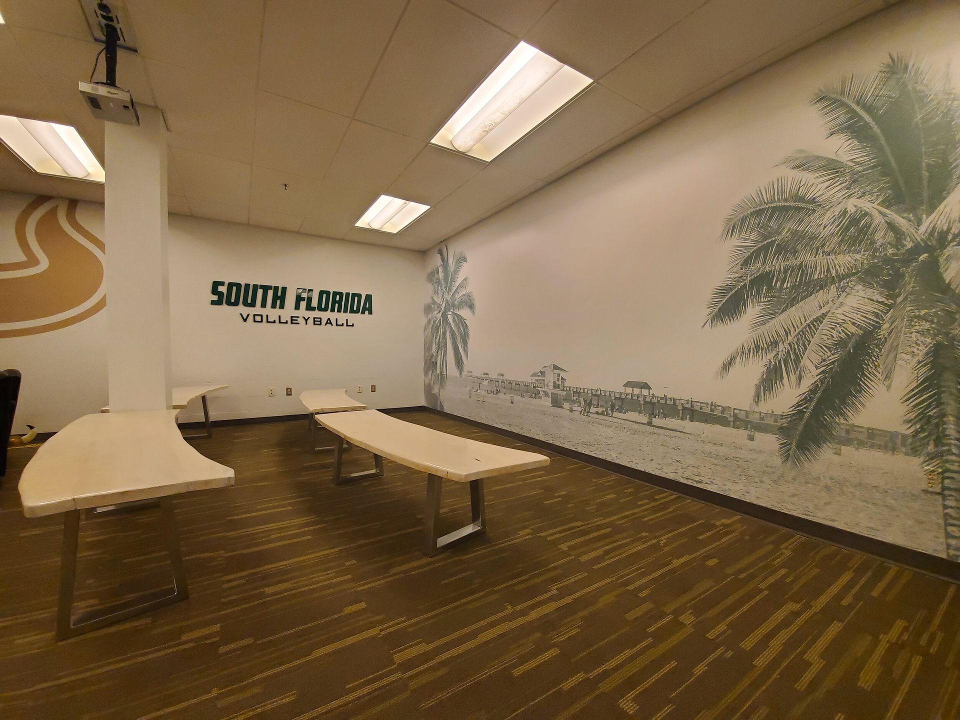 Meeting room with tables, a mural of palm trees, and a 