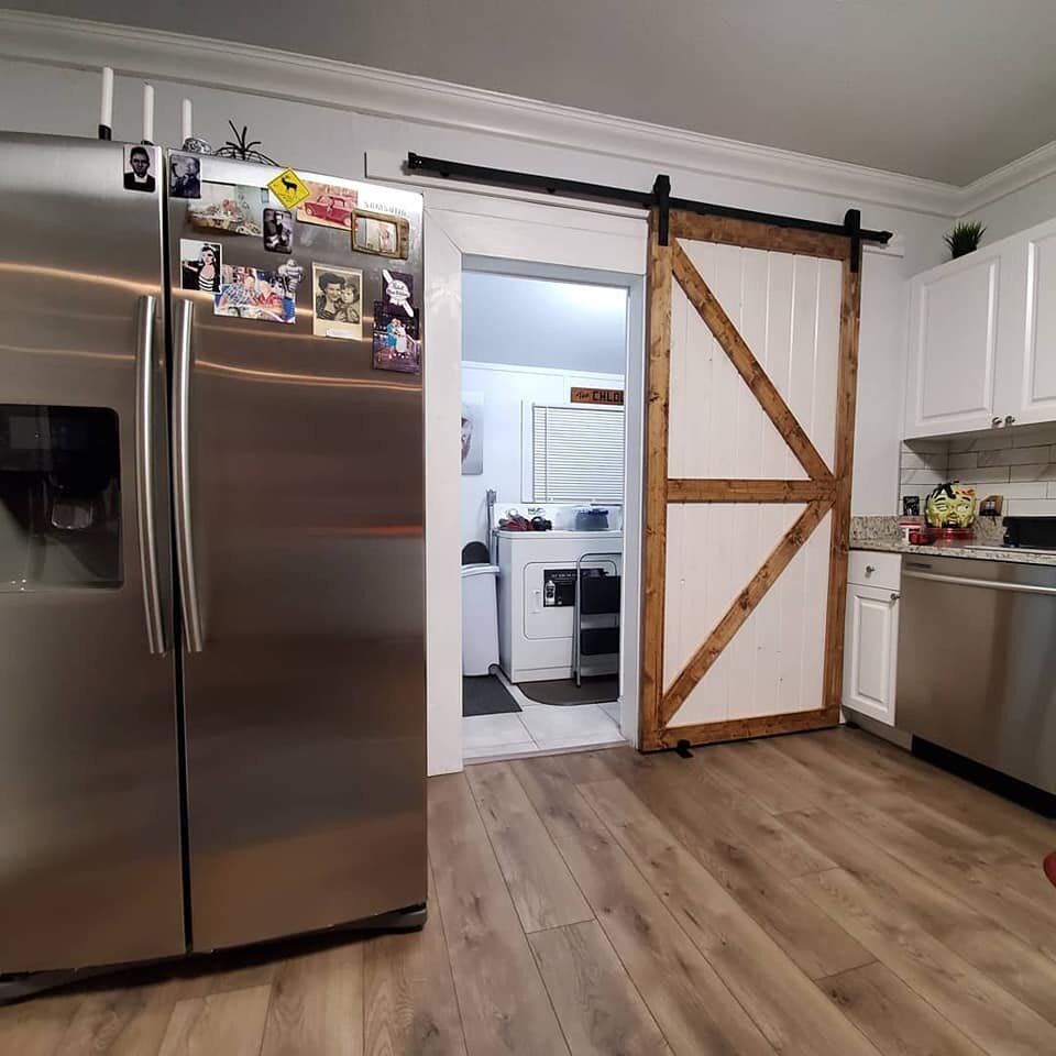 Kitchen with stainless steel appliances and a barn door leading to a laundry room.